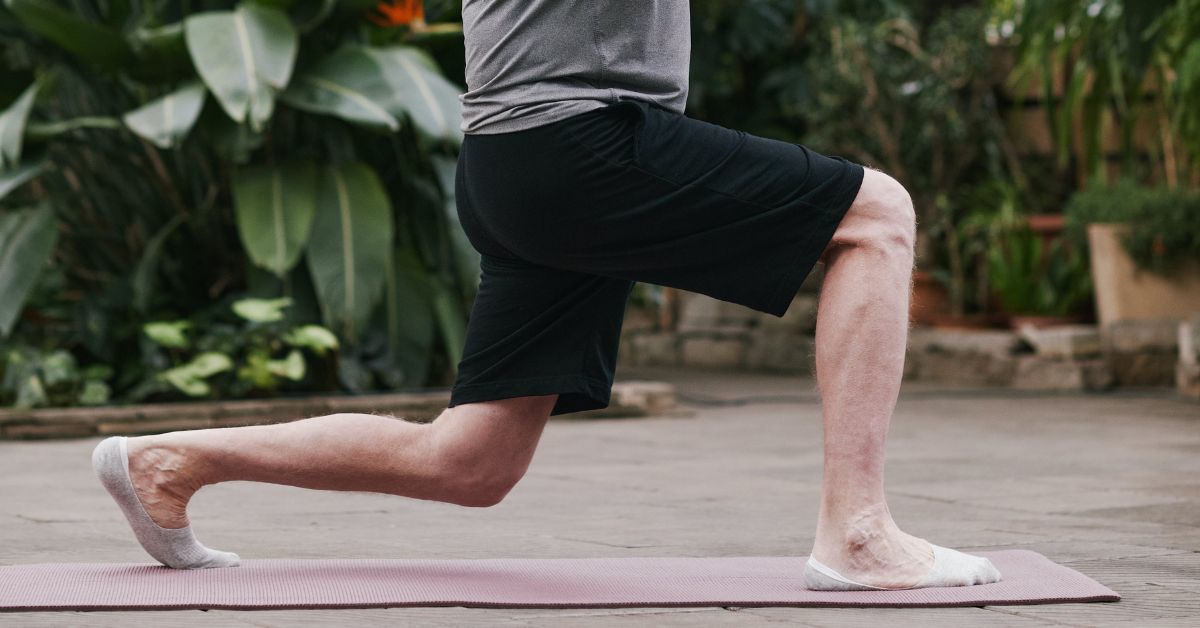 An image of a senior man's legs in a lunge position as he is doing yoga