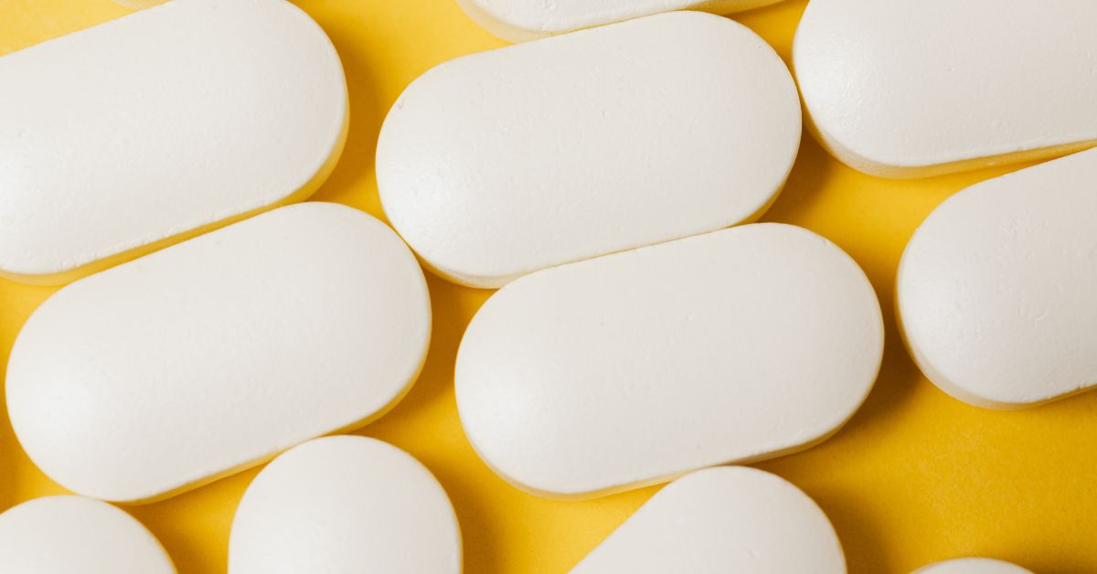 Closeup image of white pill tablets over a yellow background