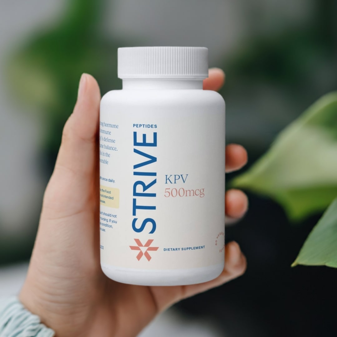 A bottle of KPV 500mcg from Strive Peptides being held in a woman's hand who is wearing a light gray sweater and standing outside.