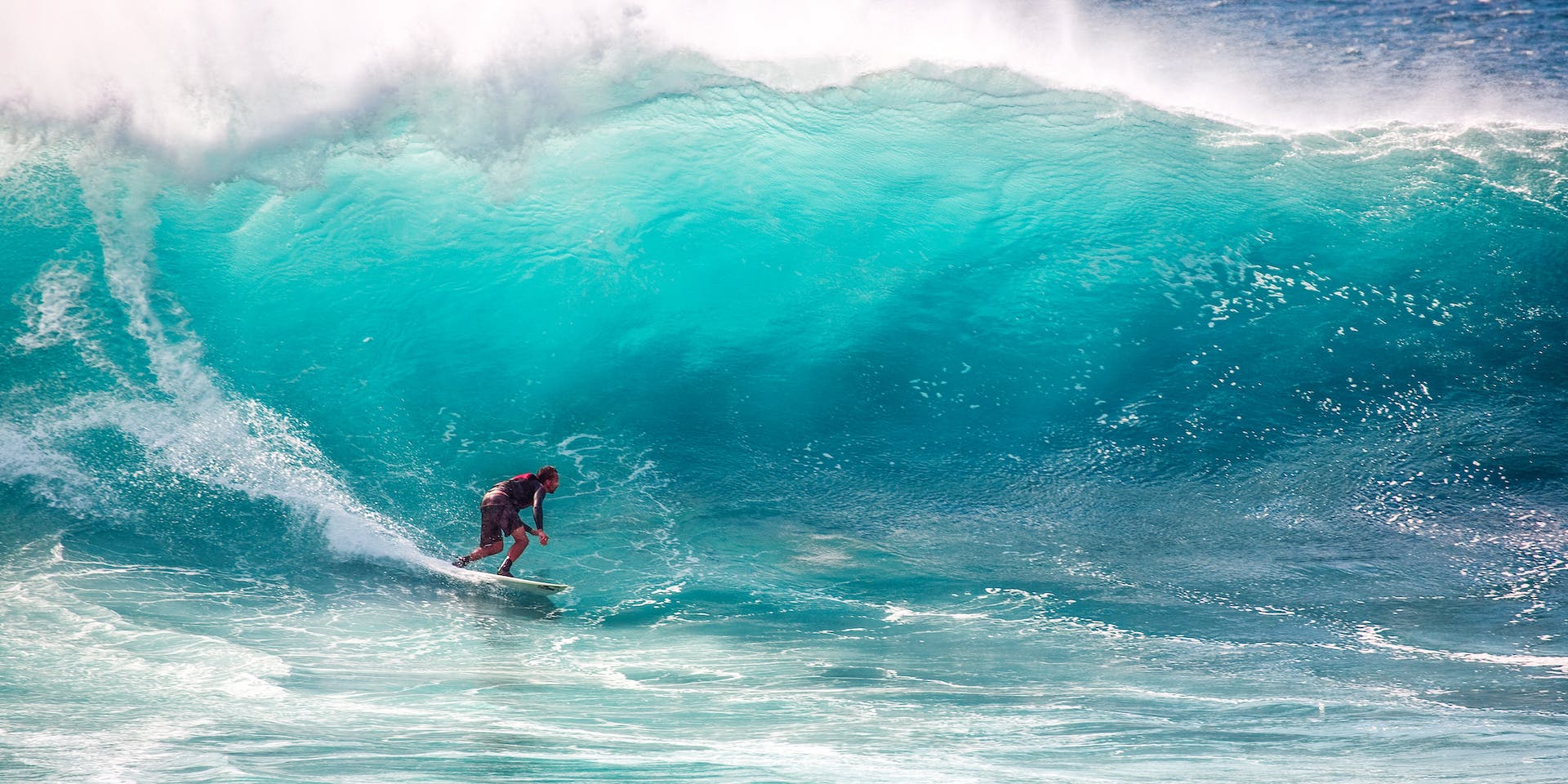 A hero image for the footer area of the Strive Peptides website showing a surfer in a bluish green ripcurl wave